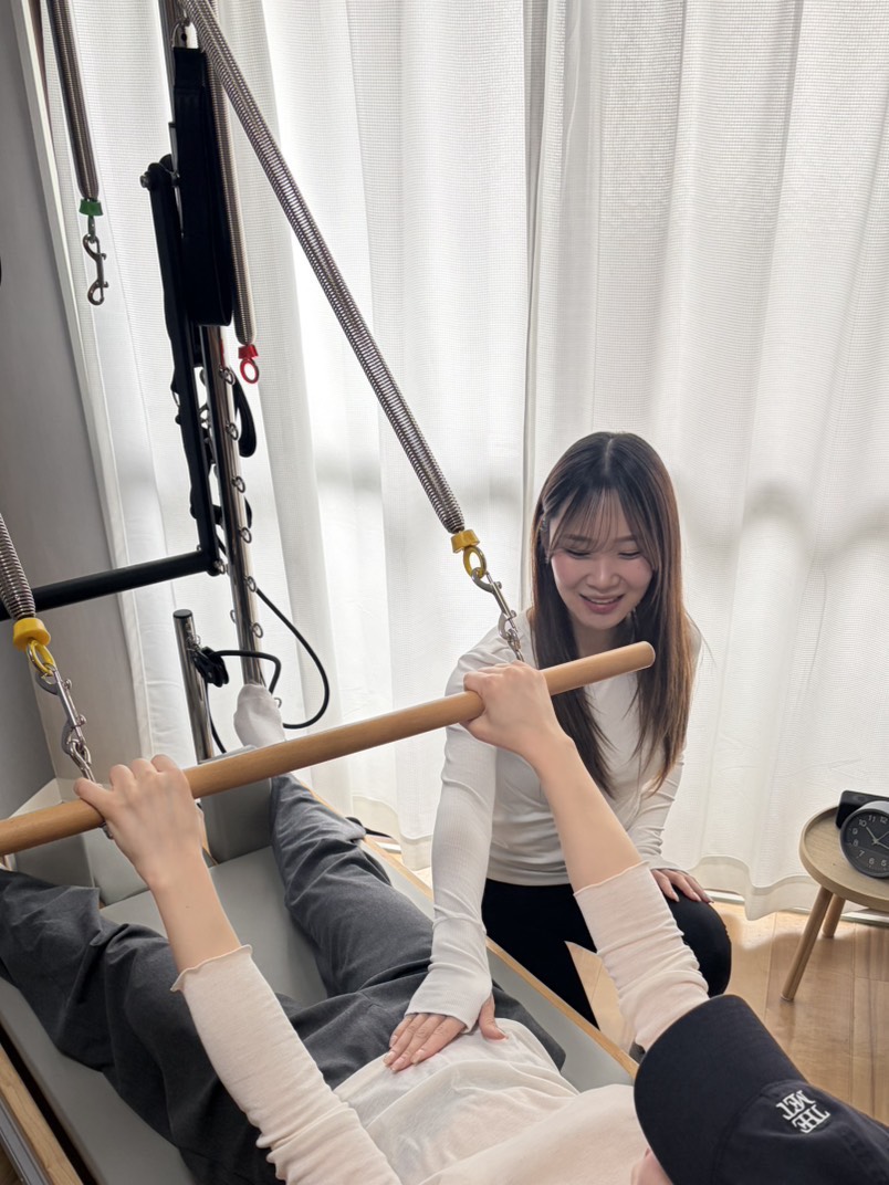 リフォーマーを使用しピラティスの指導を受けている女性