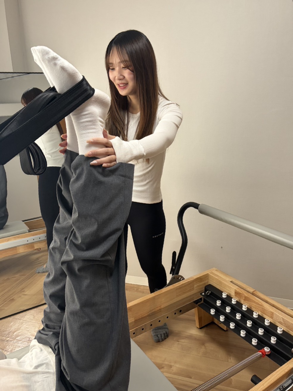 リフォーマーを使用しピラティスの指導を受けている女性